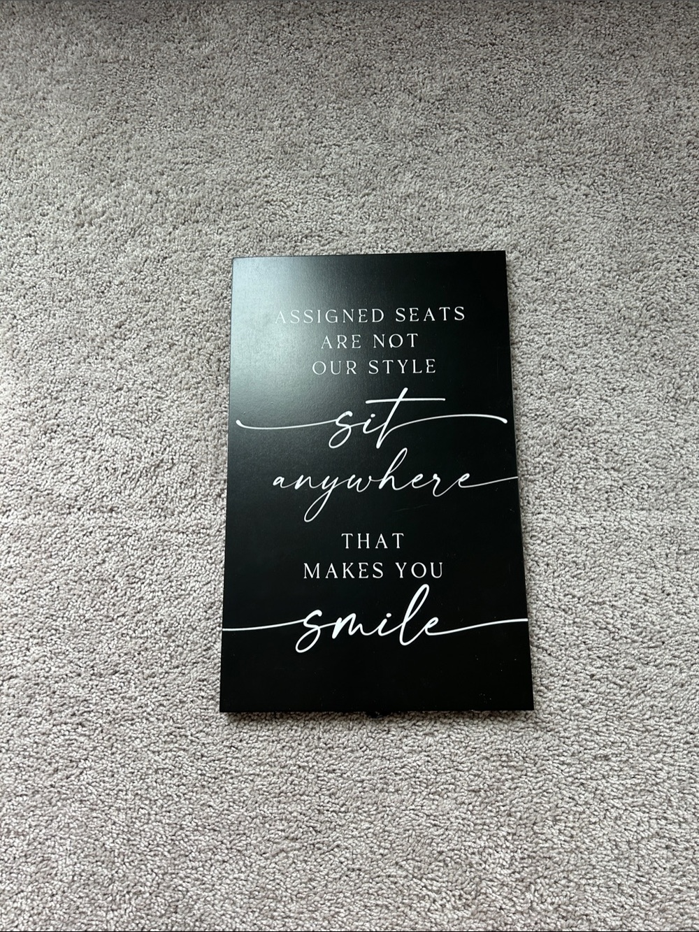 Black Wall Sign with White Script "Sit Anywhere"